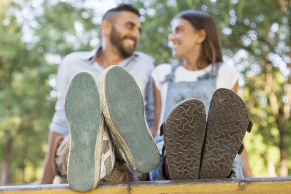 Jeune couple amoureux dans le parc avec ses pieds au premier plan — Photo