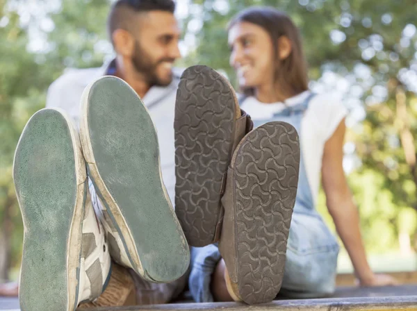 Jeune couple amoureux dans le parc avec ses pieds au premier plan — Photo