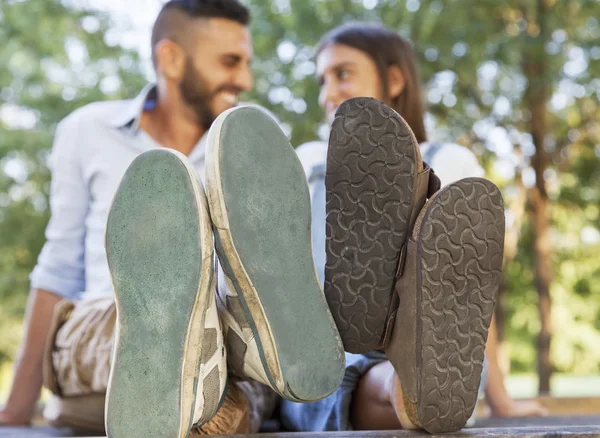 Jovem casal apaixonado no parque com os pés em primeiro plano — Fotografia de Stock