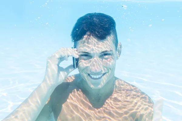 Jovem toma uma chamada para smartphone subaquático — Fotografia de Stock