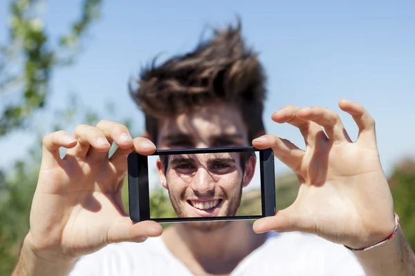 若い大人かわいいスマート フォンと selfie を取る — ストック写真