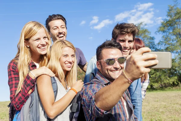 Skupina s úsměvem přátel s selfie s smartphone — Stock fotografie
