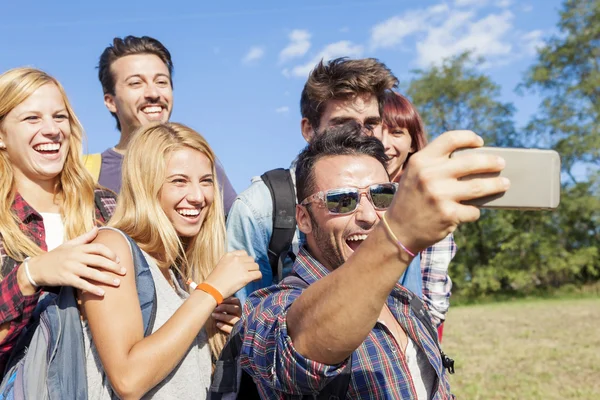 Group of smiling friends taking selfie with smartphone — Stock Photo, Image