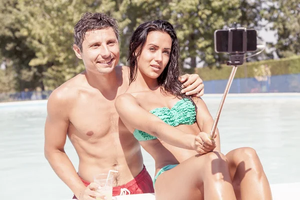 Sonriente hermosa pareja toma un selfie con teléfono inteligente poolsid — Foto de Stock