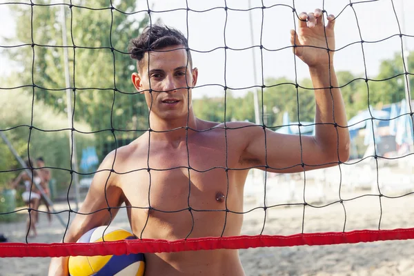 Retrato del jugador de voleibol de pie frente a la red en la playa —  Fotos de Stock