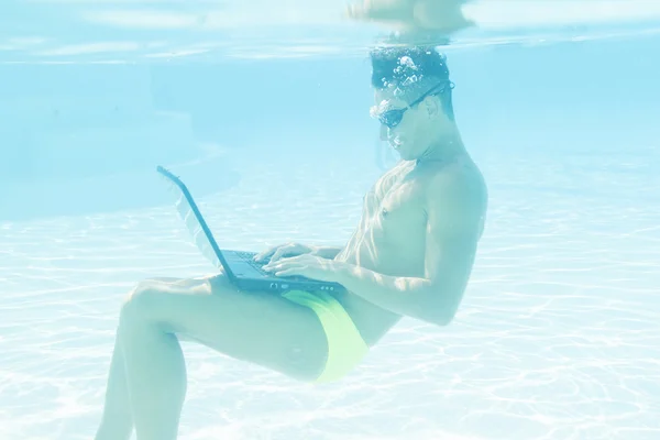 Young man working with his laptop underwater — Stok fotoğraf