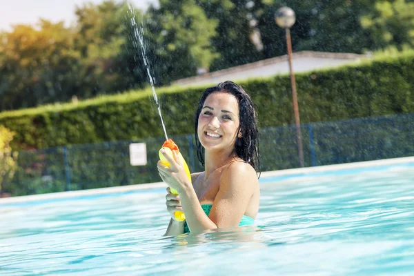 Chica bonita jugando con pistolas de agua en la piscina — Foto de Stock