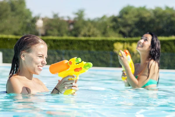 Ładne dziewczyny gry z guns wody w basenie — Zdjęcie stockowe