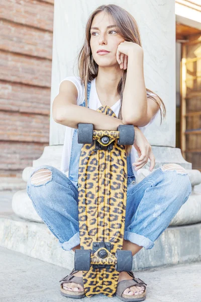 Beautiful young woman with his spotted skateboard — Stock Photo, Image