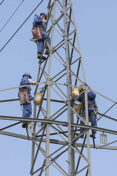 Mast strängar målare med skyddskläder på en elstolpar på jobbet. — Stockfoto