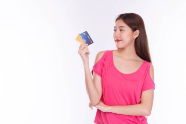 Ödeme ve finansal konsept. Neşeli genç bir kadın, elinde tutarken ve kredi kartı modeline bakarken, izole edilmiş beyaz arka plan üzerinden günlük kıyafetler giyiyor.. 