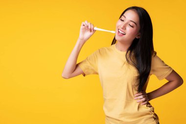 Ağız ve diş sağlığı konsepti iyi. Elinde beyaz diş fırçası olan genç bir kadın, izole edilmiş sarı arka planda fotokopi çeken kameraya bakarken gülümse.. 