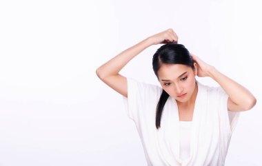 Saç bakım konsepti. Göz kamaştırıcı genç kadın, kopyalanmış beyaz arka planda otururken saç tokası kullanıyor.. 