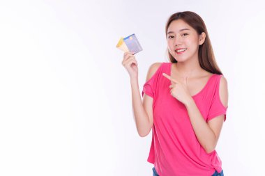 Ödeme ve finansal konsept. Neşeli genç bir kadın, günlük giysiler giyip kredi kartı modelini tutuyor ve izole edilmiş beyaz arka plandan kameraya bakıyor.. 