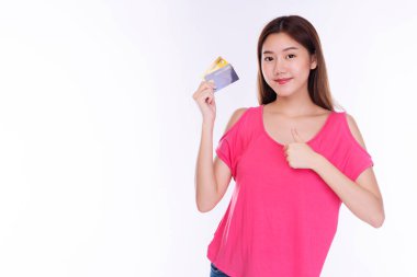  Ödeme ve finansal konsept. Neşeli genç bir kadın, günlük kıyafetler giyip kredi kartı modelini tutarken baş parmağını kaldırıyor ve izole edilmiş beyaz arka planda kameraya bakıyor..