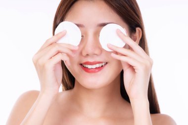 Sağlıklı cilt ve kozmetik konsepti. Gülümseme portresi beyaz arka planda tek başına dururken elinde beyaz pamuk pedi tutan genç bir kadın.. 