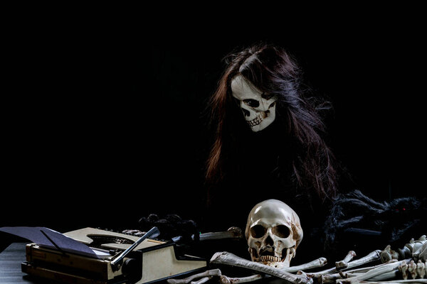 Ghostly skull typing something on table on black background. Ghost using Typewriter text with paper message on isolated. Halloween concept.