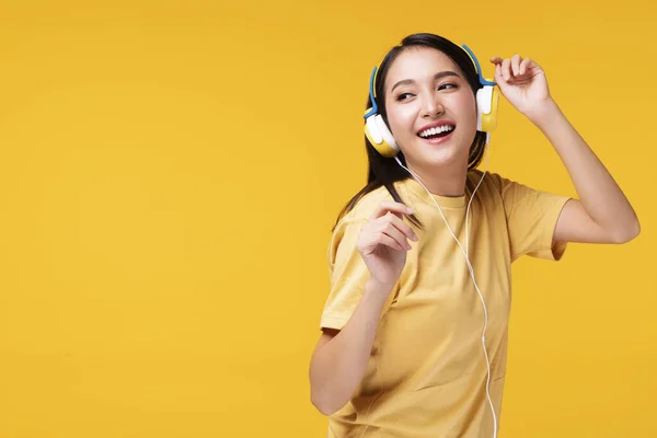 趣味の概念を持つライフスタイルレジャー 陽気音楽フォームスマートフォンを聞いてヘッドフォンを身に着けている若い女性を楽しみ 孤立した黄色の背景の上にリラックスダンス — ストック写真
