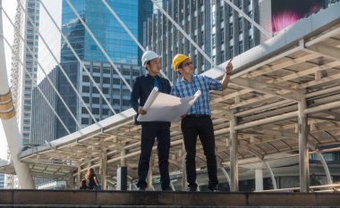 İnşaat alanında bir projeye bakan genç mühendisleri olan genç bir iş adamı..