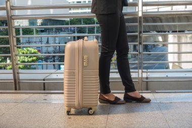 Seyahat işindeki kadın valizini çekiyor ve şehirde yürüyor.