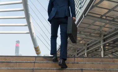 Arka işadamı şehirde merdivenlerden çıkan bir evrak çantası taşıyor..