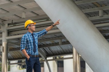 Sarı şapkalı genç mühendis şehirde ileriyi işaret ediyor..
