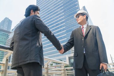 İki genç iş adamı şehirde el sıkışırken.