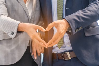 Çift kalplerini elleriyle gösteriyor..