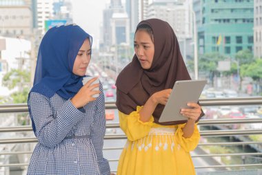 Sarı giyinmiş Arap kadınlar, arkadaşlarına tablet tutuyorlar..
