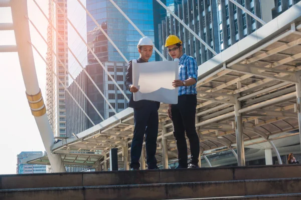 İnşaat alanında bir projeye bakan genç mühendisleri olan genç bir iş adamı..