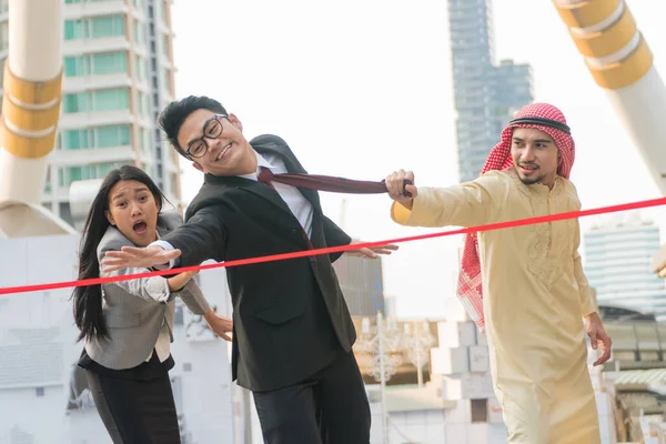 一位年轻商人试图与一位阿拉伯商人拉上领带 以抓住背后的红丝带 — 图库照片