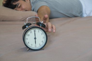 Yatakta uyuyan yakışıklı adam, çalar saate ulaşıyor..