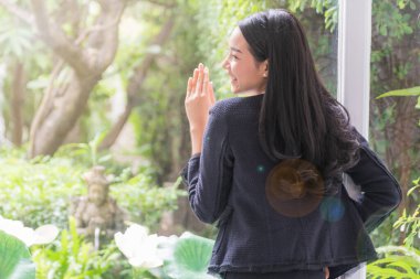 Güzel genç bir kadın oturma odasında cam duvara bakıyor.