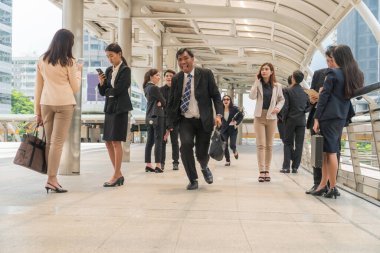 Bir evrak çantası taşıyan orta yaşlı bir işadamı, şehirde yürüyen insanlar arasında işe gitmek için acele ediyor..