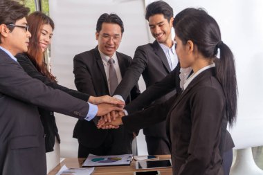 Grup işadamları toplantının başarısından sonra el ele tutuşuyorlar. İş adamı ekibi iş anlaşması, başarı ve takım çalışması kavramını el ele veriyor.