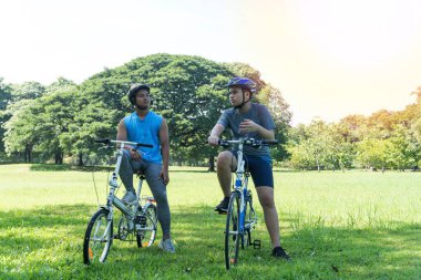 Bisikletin üzerinde duran ve parkta konuşan iki ergen çocuk. Yaşam tarzı konsepti