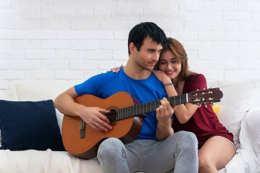 Aşık neşeli bir çift. İçerideki genç çiftin çarpıcı şehvetli portresi. Beyaz koltukta sevgili kızı için akustik gitar çalan çekici genç bir adam. Aile samimiyetini kavra 