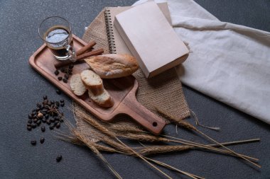 Bir fincan sade kahve, ahşap tabakta ekmek, masada kuru çiçek..