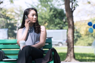 Kavram zamanı rahatlatır. Akıllı telefondan konuşan çekici bir iş kadını. Parkta bankta oturmuş kahvesini yudumluyor..