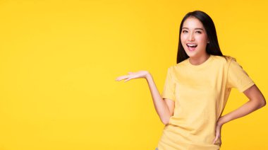 Reklam malzemeleri sunumu. Neşeli genç bir kadın elini ürün ya da boş fotokopi alanıyla tutarken sarı arka planda tek başına duruyor.