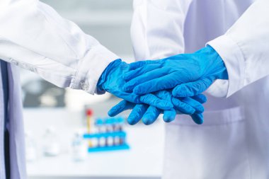 Hastanede ya da laboratuarda takım çalışması yapmak ve takım konseptine güvenmek. Mavi koruyucu eldiven giyen bir grup bilim adamı ya da doktor ve hemşire birlikte çalışırlar.. 