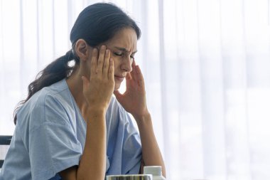 Kronik baş dönmesi sağlıksız ya da sigorta konsepti. Hasta genç bir kadın hastane odasında otururken stres dolu baş ağrısı ve migren sorunları yaşıyor.. 