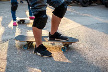 Aktivite boş zaman kaykay yaşam tarzı konsepti. Sörf yapan atletik adamın bacakları akşamları gün ışığında spor yaparken yolda kayıyor..