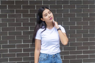 Uzun saçlı yorgun bir kadın beton duvarların arkasında dikilirken kendini çok ateşli hissediyor. Asyalı kız, yüz için kağıt temizleme yağı kullanıyor. Taze ve temiz bir cilt..