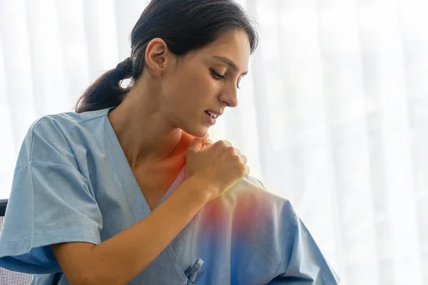 Insurance and health care sickness concept. Unhappy patient young woman holding hand on own pain shoulder or office syndrome or injury neck while sitting in the room at hospital.