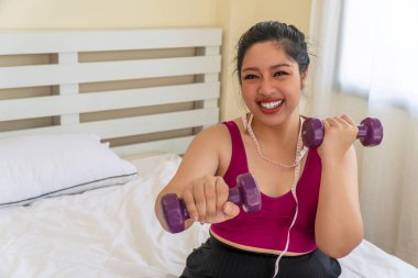 Aktivite egzersizi diyet ya da obezite konsepti için uygun vücut. Ölçüm bandıyla boynunda halteri tutan şişman kadın yatakta otururken diyet yapıyor..