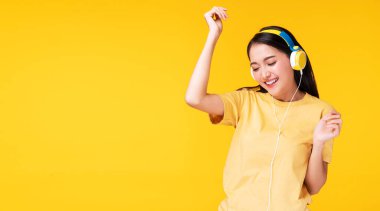 Neşeli, kulaklık takan, akıllı telefon dinleyen ve dans eden genç bir kadın izole edilmiş sarı arka planda rahatlıyor. Hobi konsepti olan yaşam tarzı eğlencesi.