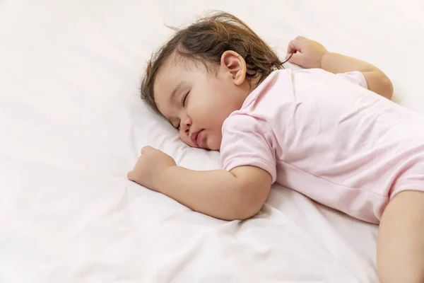Küçük kız 12 ay boyunca pembe bez giyerek beyaz yatakta uyudu. Bir yaşında tatlı bir çocuk karışık bir ırk uyuyor güzel bir rüya görüyor yatak odasında dinleniyor. 