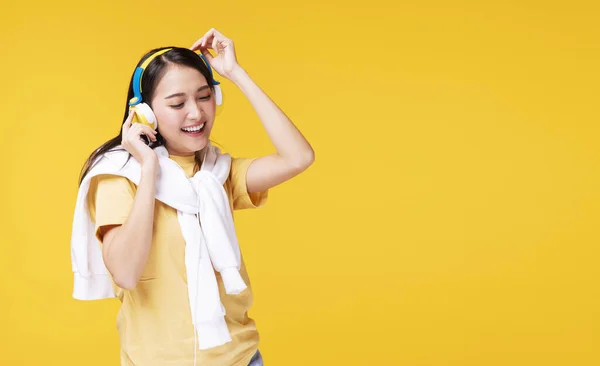音楽を聴くヘッドフォンを装着した若い女性がスマートフォンを形成し 孤立した黄色の背景の上でリラックスして踊る陽気 趣味をコンセプトにしたライフスタイルレジャー — ストック写真