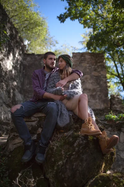 Mladý pár v lásce objímání v přírodě. Sedí na velký kámen — Stock fotografie